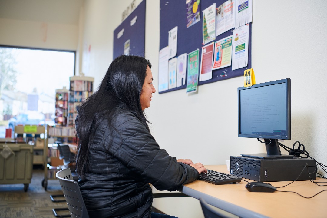 Woman with black hair sitting at desk and typing on computer