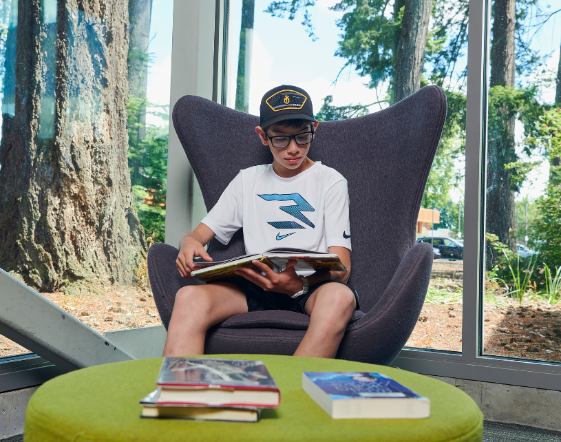 Teen boy sitting in chair and reading a book