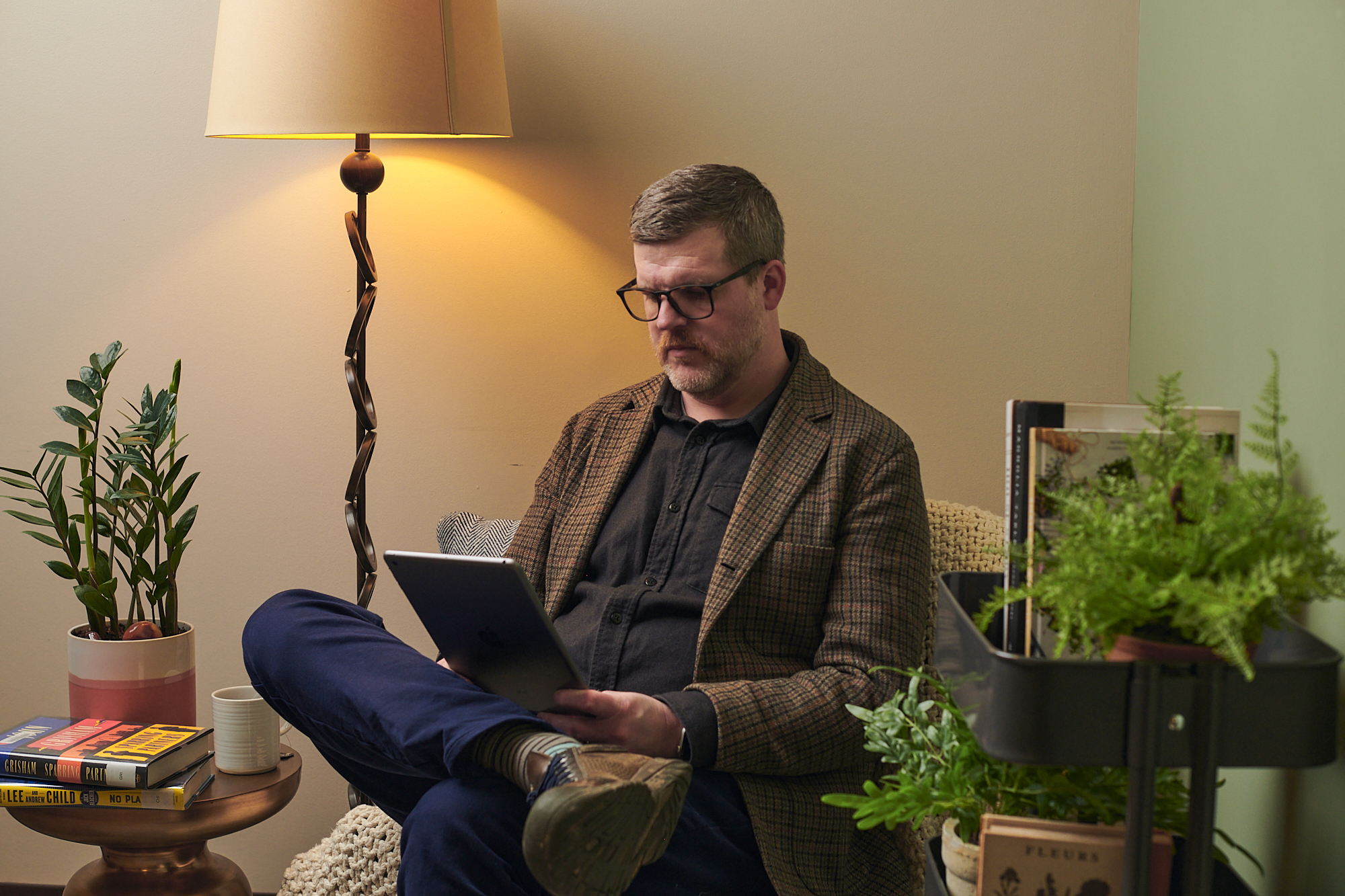 Man wearing glasses sitting in chair holding tablet